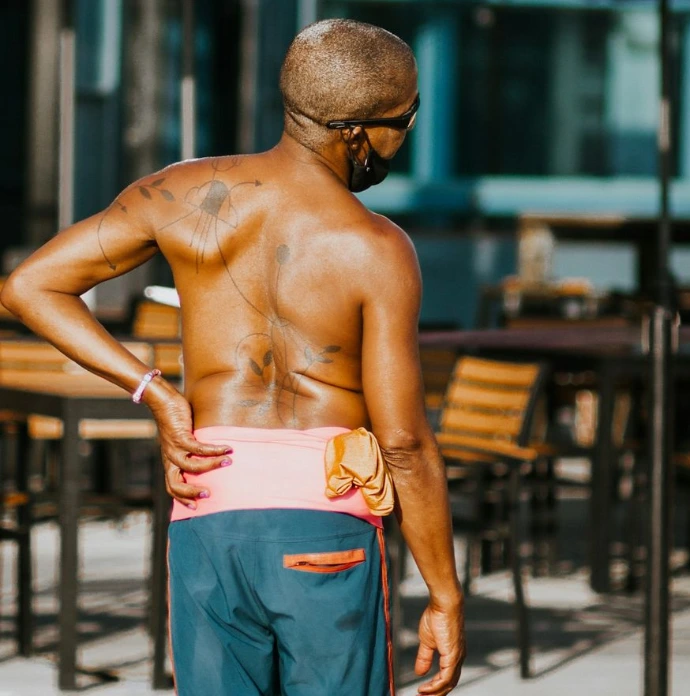 topless man in blue denim jeans standing near brown wooden table